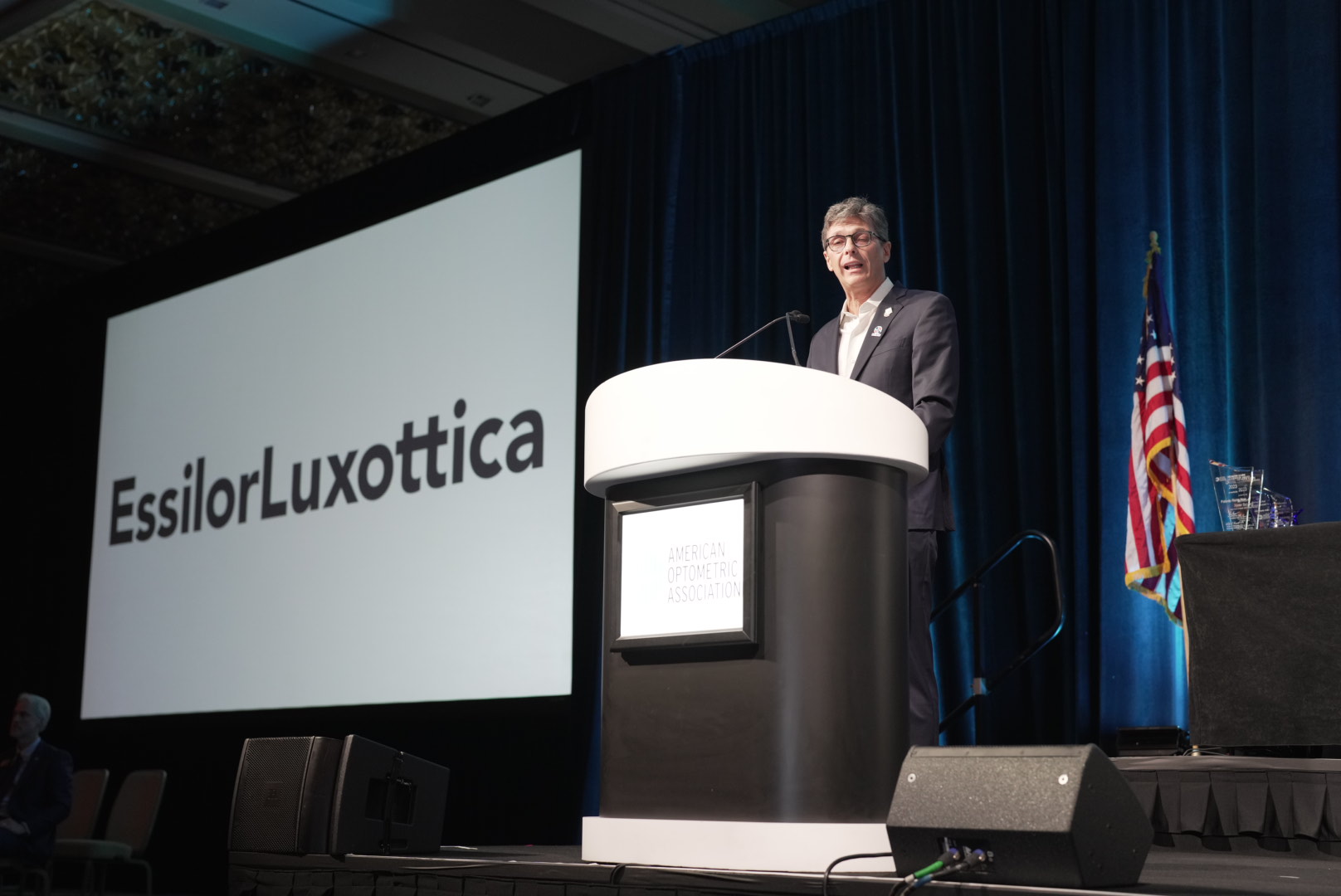 Conference keynote speaker at podium - EssilorLuxottica AOA