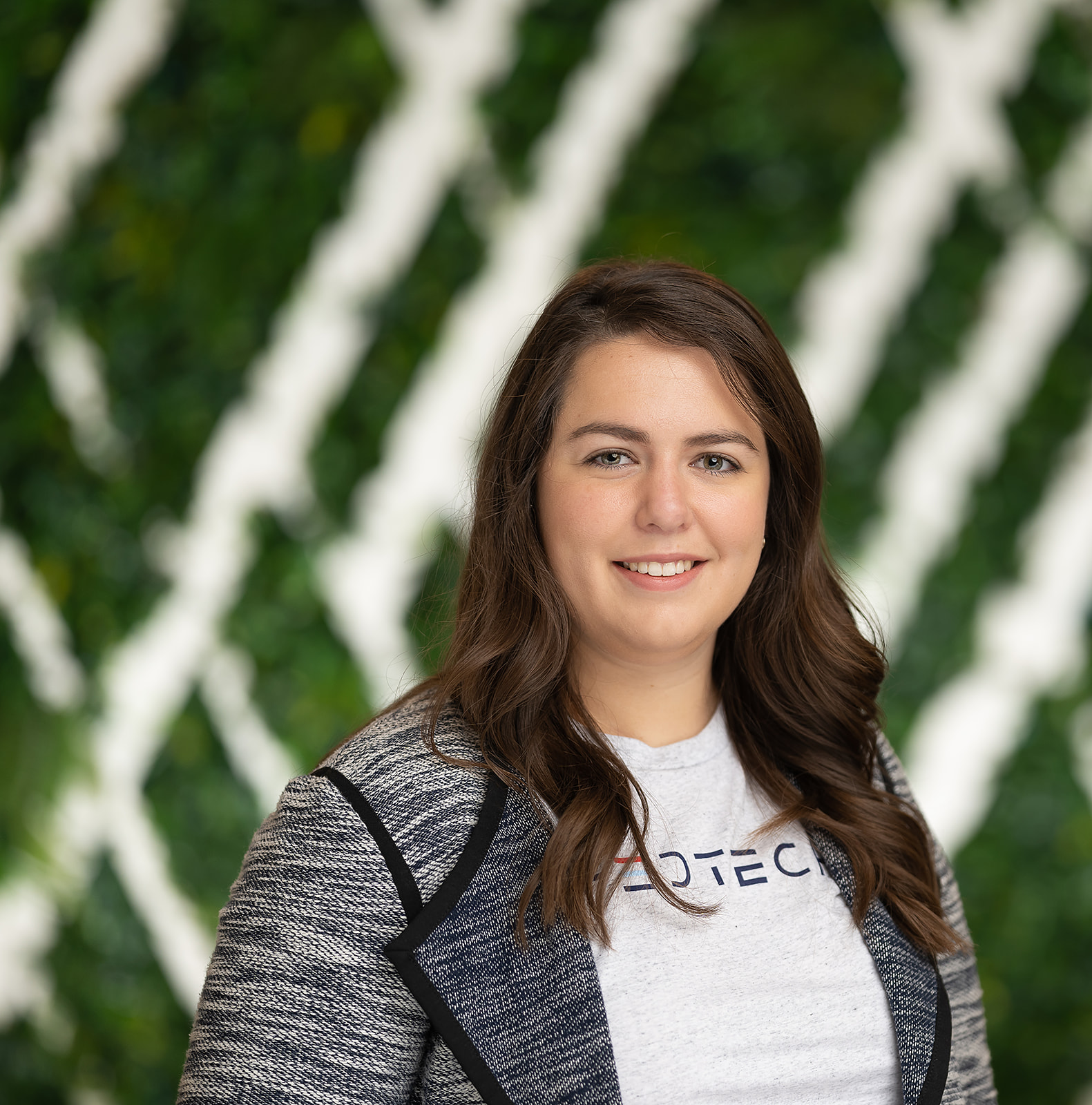 FedTech team portrait - woman in blazer green wall backdrop